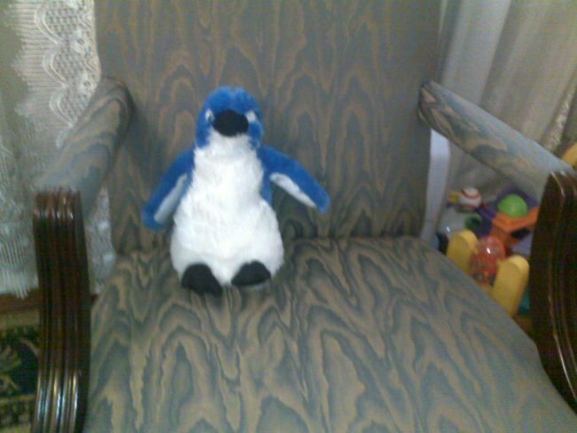 stuffed penguin sitting on a chair like it's interviewing