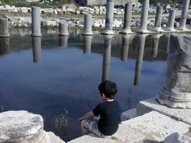 photo of child with broken roman columns in the background