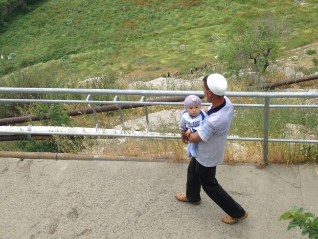 photo of a man in Southern Kyrgyzstan carrying a baby