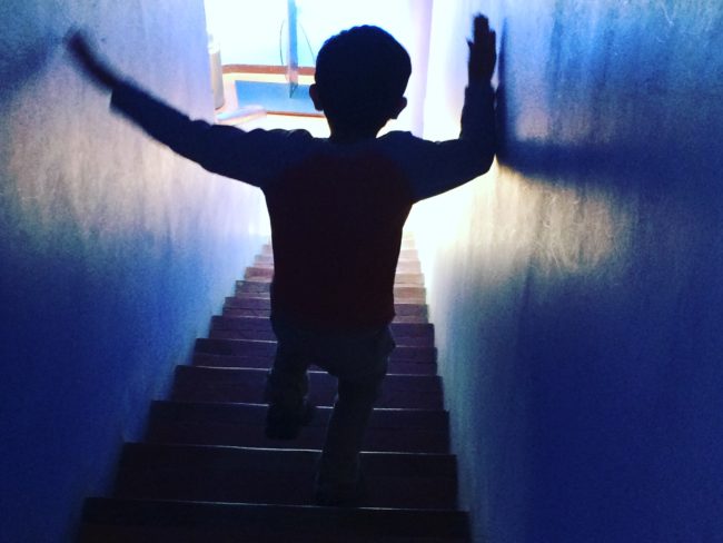 Child walking down a tunnel toward light.