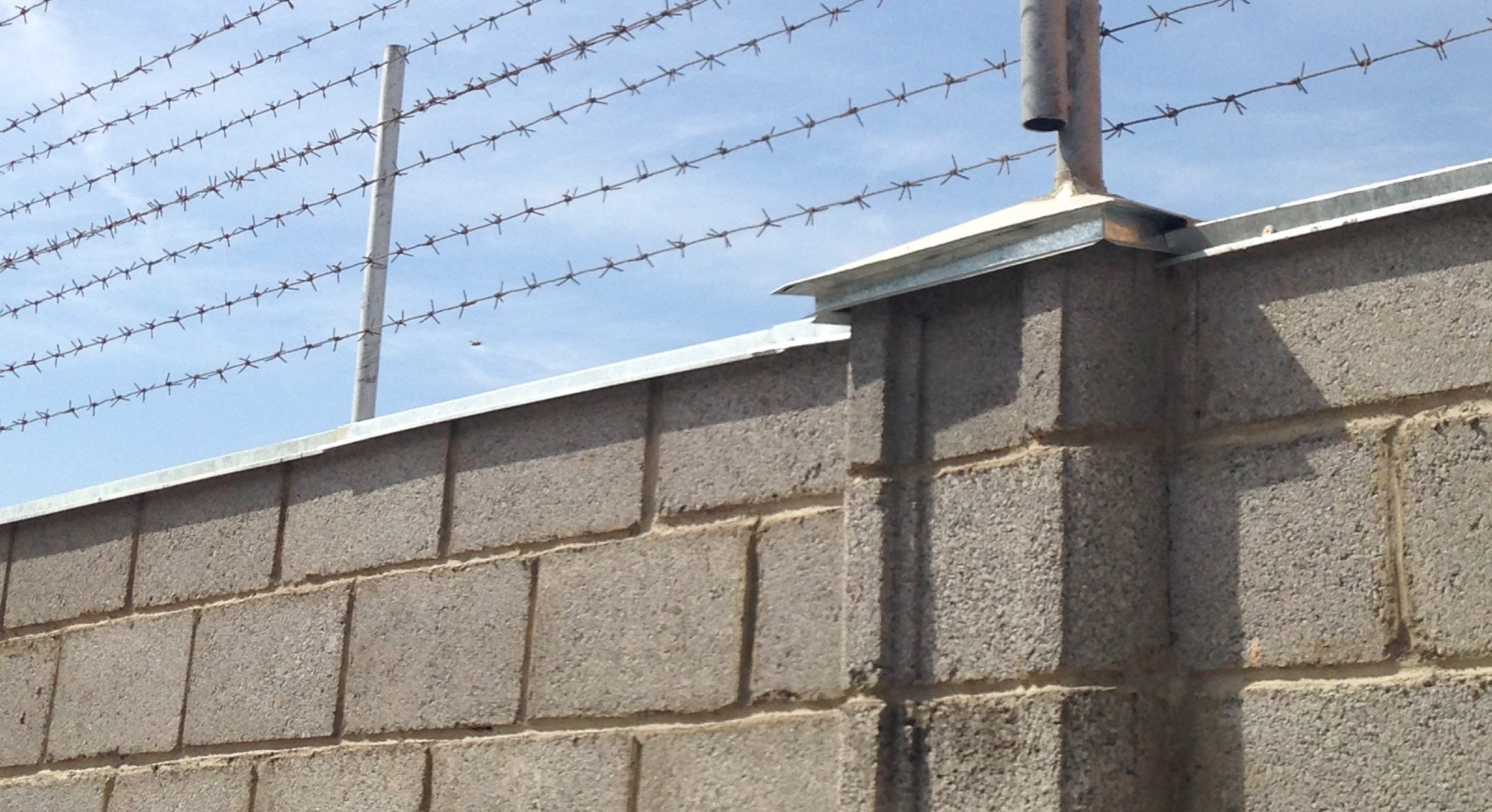 photo of brick wall with barbed wire across the top
